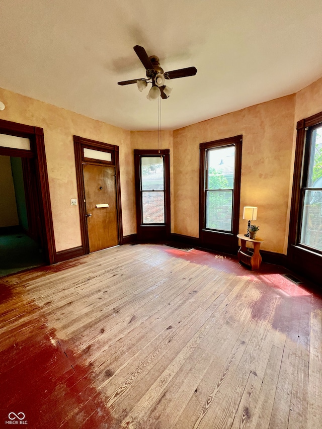 empty room with visible vents, baseboards, a ceiling fan, and hardwood / wood-style flooring