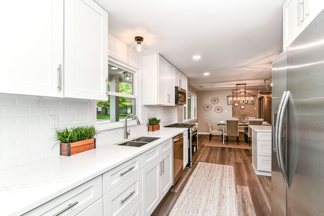 7118 Mikesell Dr, Indianapolis, IN 46260 - kitchen with appliances with stainless steel finishes, a sink, white cabinetry, backsplash, and dark wood-style flooring