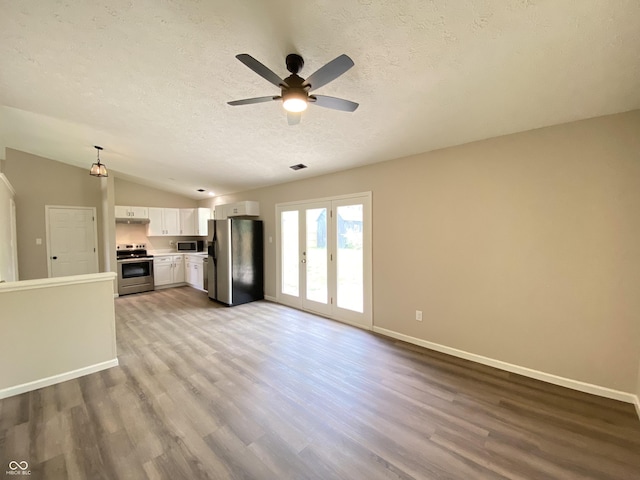 unfurnished living room featuring vaulted ceiling, ceiling fan, a textured ceiling, and wood finished floors