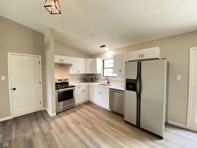 kitchen featuring light wood-style flooring, under cabinet range hood, a sink, white cabinetry, and stainless steel appliances