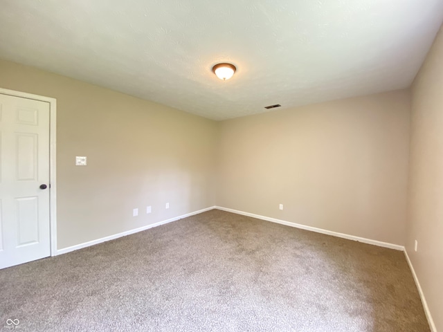 spare room featuring baseboards, visible vents, and carpet floors