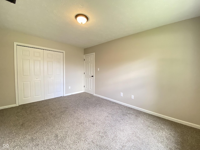 unfurnished bedroom featuring a closet, baseboards, and dark carpet