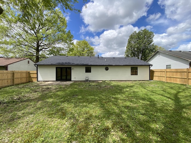 rear view of house featuring a yard, a fenced backyard, and a patio