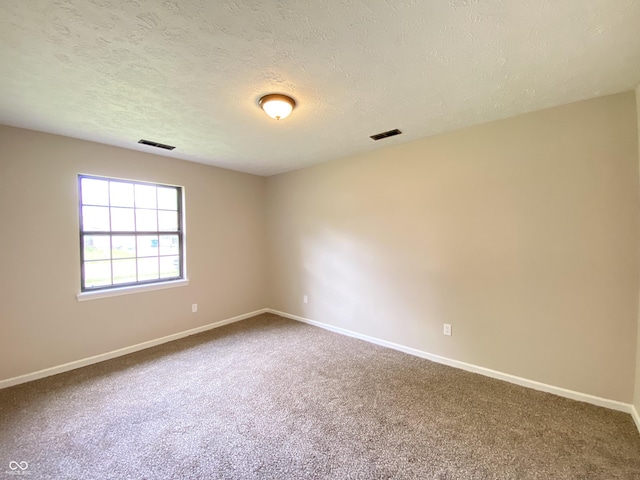 spare room featuring a textured ceiling, visible vents, baseboards, and carpet floors