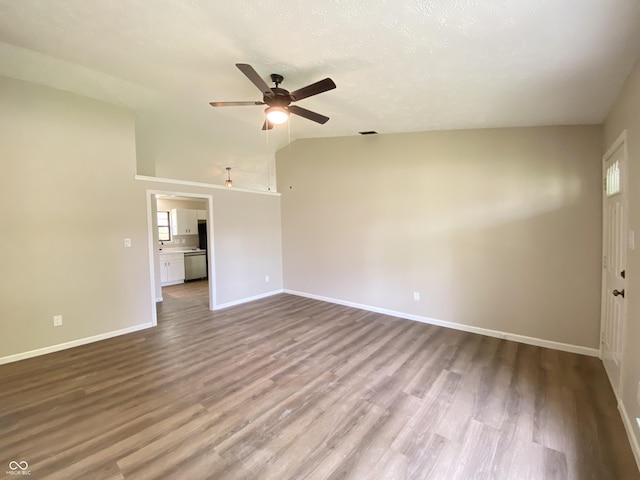 empty room featuring a ceiling fan, vaulted ceiling, baseboards, and wood finished floors