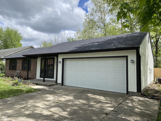view of front facade with driveway, roof with shingles, and an attached garage