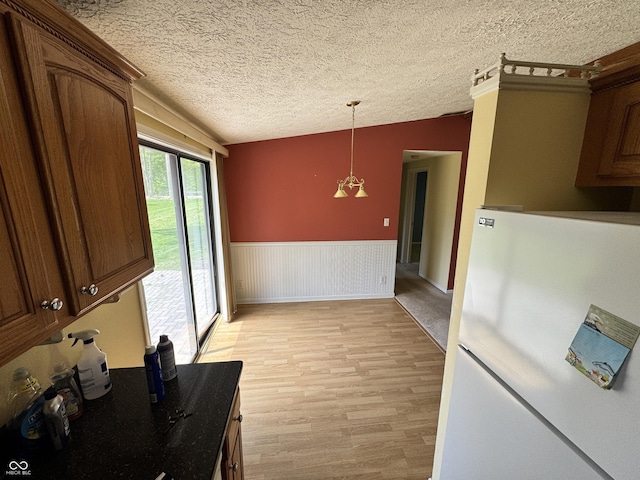 575 Mill Spgs, Coatesville, IN 46121 - unfurnished dining area with lofted ceiling, a textured ceiling, light wood-style flooring, and a wainscoted wall