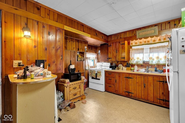 205 E Washington St, Roachdale, IN 46172 - kitchen featuring a sink, brown cabinetry, white appliances, wood walls, and light floors