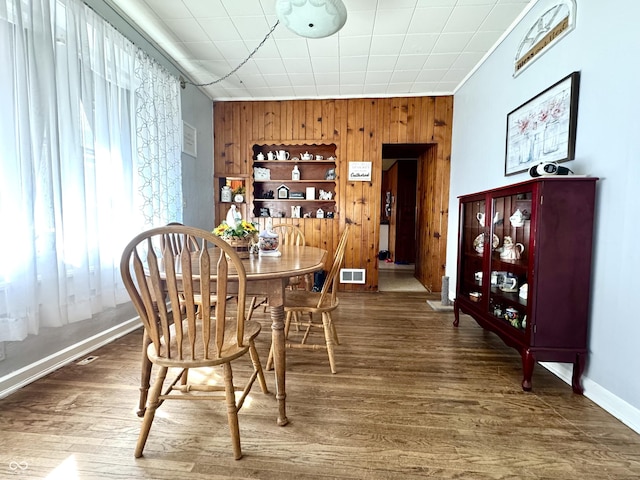 205 E Washington St, Roachdale, IN 46172 - dining room featuring baseboards, visible vents, wooden walls, an accent wall, and wood finished floors