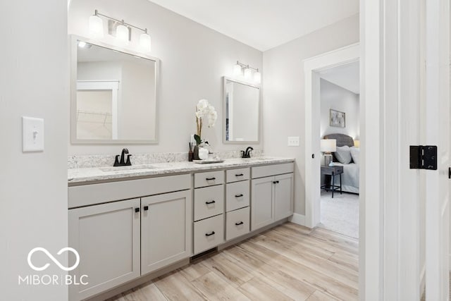 full bathroom featuring baseboards, double vanity, a sink, and wood finished floors