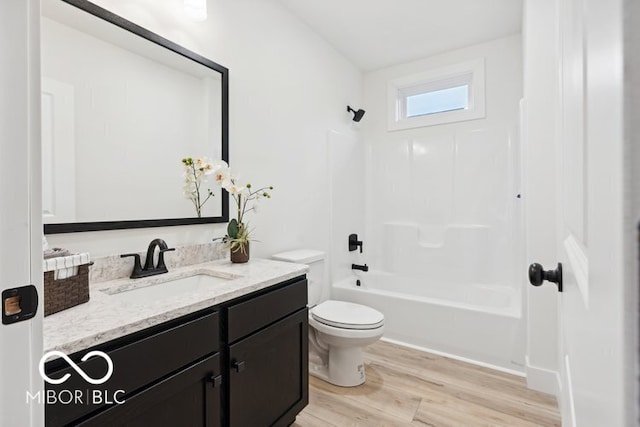 full bathroom featuring toilet, wood finished floors, vanity, and washtub / shower combination
