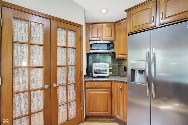 11471 Clarkston Rd, Zionsville, IN 46077 - kitchen with appliances with stainless steel finishes, backsplash, french doors, brown cabinets, and dark stone counters
