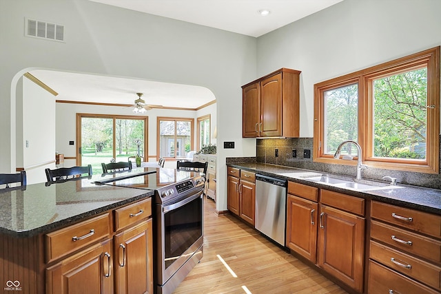 11471 Clarkston Rd, Zionsville, IN 46077 - kitchen with appliances with stainless steel finishes, arched walkways, a sink, light wood finished floors, and dark stone countertops