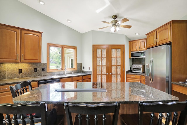 11471 Clarkston Rd, Zionsville, IN 46077 - kitchen featuring appliances with stainless steel finishes, a kitchen bar, vaulted ceiling, tasteful backsplash, and brown cabinetry