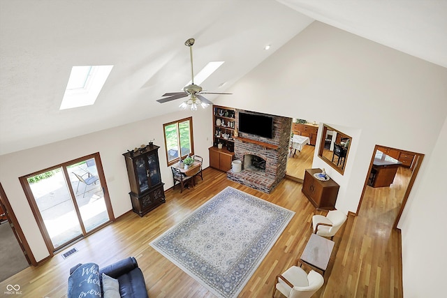 11471 Clarkston Rd, Zionsville, IN 46077 - living area featuring a skylight, high vaulted ceiling, light wood finished floors, a brick fireplace, and ceiling fan