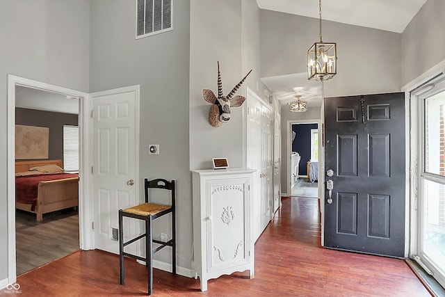 entryway with high vaulted ceiling, wood finished floors, a chandelier, plenty of natural light, and baseboards
