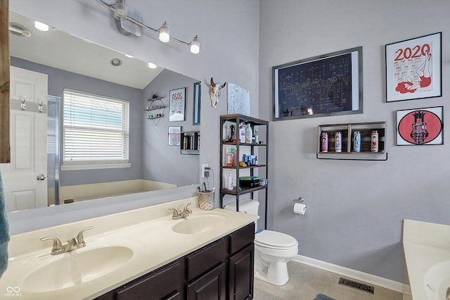 bathroom with a garden tub, tile patterned flooring, toilet, double vanity, and baseboards
