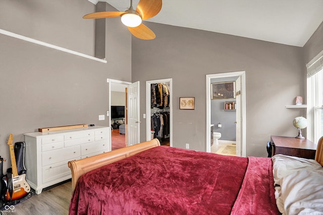 bedroom with high vaulted ceiling, a spacious closet, ensuite bath, light wood finished floors, and baseboards