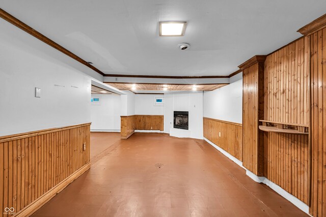 finished below grade area featuring wooden walls, a fireplace, a wainscoted wall, and crown molding