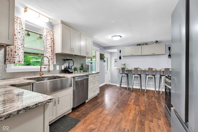 kitchen with appliances with stainless steel finishes, a sink, tasteful backsplash, and plenty of natural light