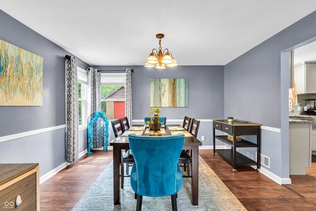 dining room featuring a chandelier, dark wood-type flooring, and baseboards