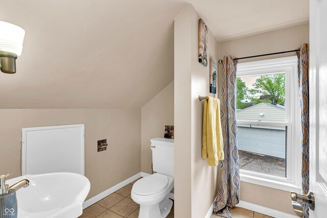bathroom with a sink, toilet, tile patterned floors, baseboards, and lofted ceiling