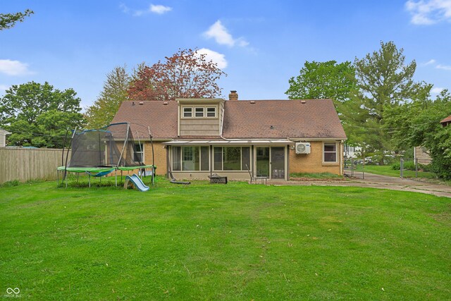 back of house with a trampoline, a sunroom, a chimney, and brick siding