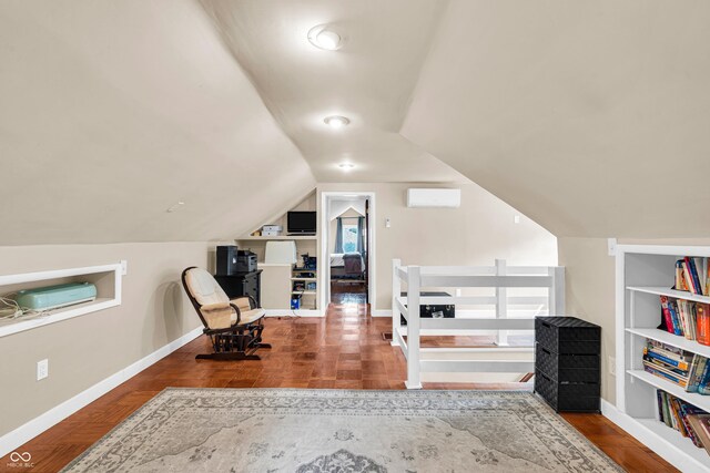 sitting room with a wall mounted air conditioner, vaulted ceiling, baseboards, wood finished floors, and an upstairs landing