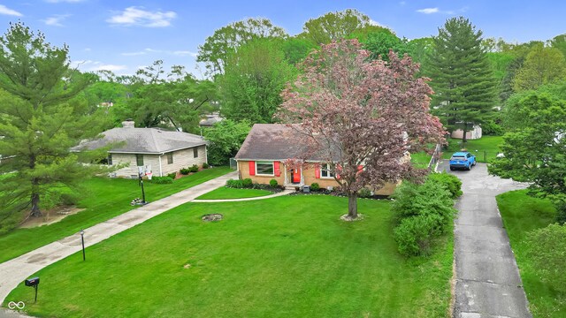 view of front of home featuring asphalt driveway and a front lawn