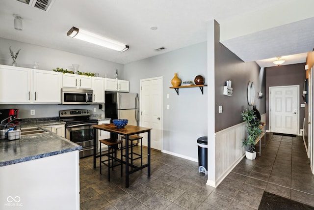 7045 Gavin Dr, Indianapolis, IN 46217 - kitchen featuring appliances with stainless steel finishes, a sink, dark countertops, white cabinetry, and dark tile patterned flooring