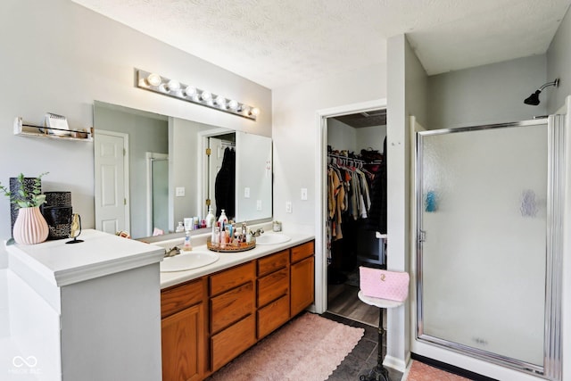 7045 Gavin Dr, Indianapolis, IN 46217 - bathroom with a stall shower, double vanity, a walk in closet, and a textured ceiling