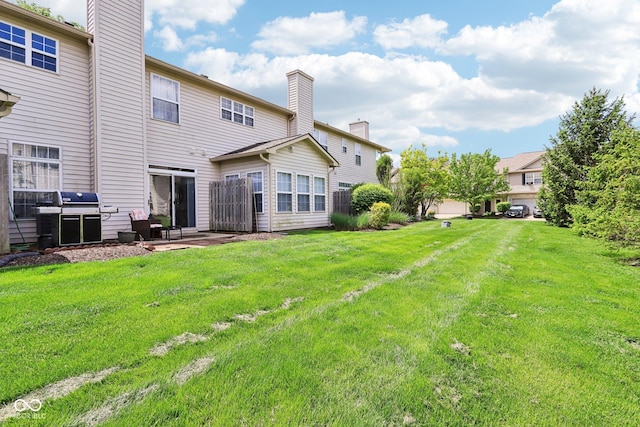 7045 Gavin Dr, Indianapolis, IN 46217 - back of property with a chimney, a lawn, and a patio