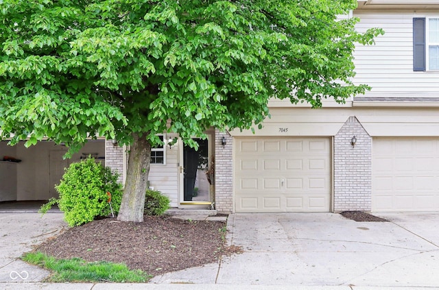 7045 Gavin Dr, Indianapolis, IN 46217 - obstructed view of property featuring brick siding, concrete driveway, and an attached garage
