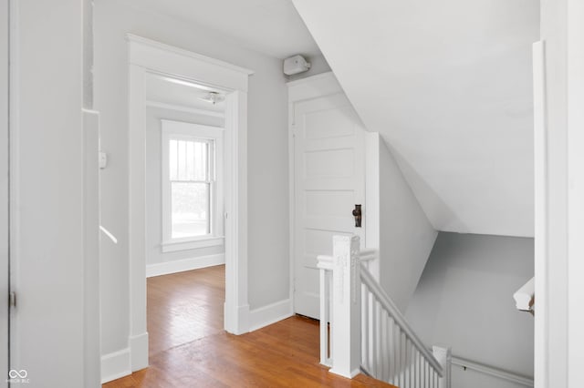 hall with an upstairs landing, wood finished floors, and baseboards