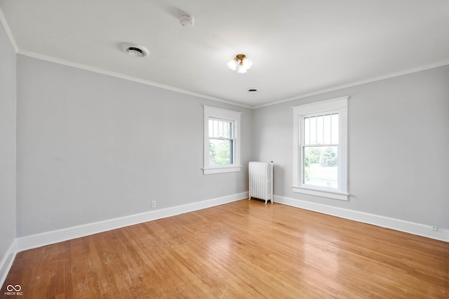 unfurnished room featuring radiator heating unit, ornamental molding, baseboards, light wood-style flooring, and a smoke detector
