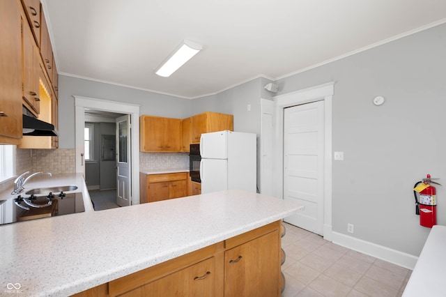 kitchen with freestanding refrigerator, under cabinet range hood, black oven, tasteful backsplash, and a peninsula