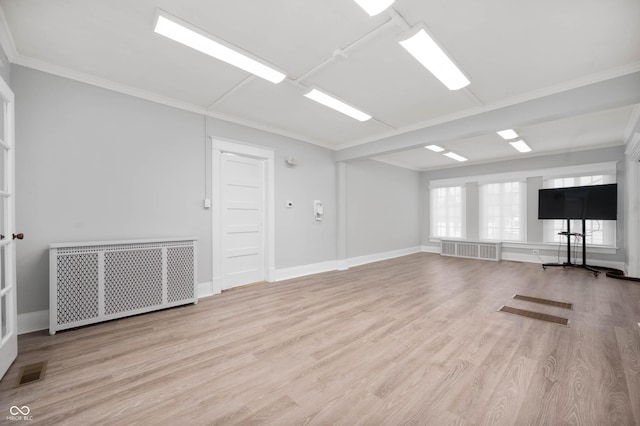 workout area with radiator, wood finished floors, ornamental molding, and baseboards