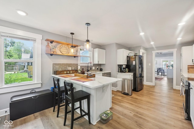 4245 Guilford Ave, Indianapolis, IN 46205 - kitchen featuring stainless steel refrigerator with ice dispenser, a peninsula, white cabinetry, decorative backsplash, and light wood-type flooring