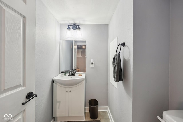 4245 Guilford Ave, Indianapolis, IN 46205 - bathroom featuring vanity, toilet, baseboards, and a textured wall