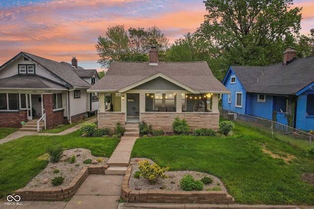 4245 Guilford Ave, Indianapolis, IN 46205 - view of front of home with a porch, a chimney, central AC unit, stone siding, and a shingled roof
