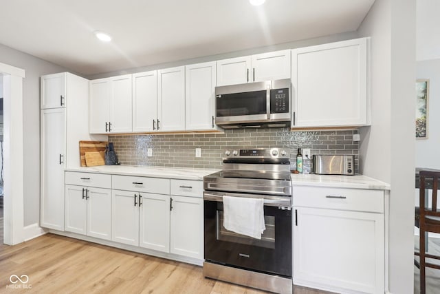 4245 Guilford Ave, Indianapolis, IN 46205 - kitchen with stainless steel appliances, light wood-style floors, backsplash, white cabinets, and light stone countertops