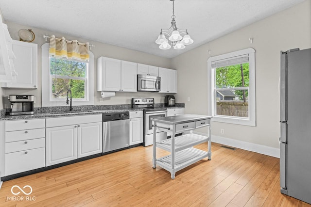 1505 Spann Ave, Indianapolis, IN 46203 - kitchen featuring appliances with stainless steel finishes, a sink, a chandelier, white cabinets, and hanging light fixtures
