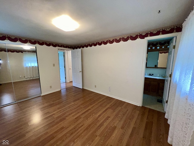 1949 Shenandoah Pl, Indianapolis, IN 46229 - unfurnished bedroom featuring wood finished floors, ensuite bathroom, a closet, baseboards, and a sink