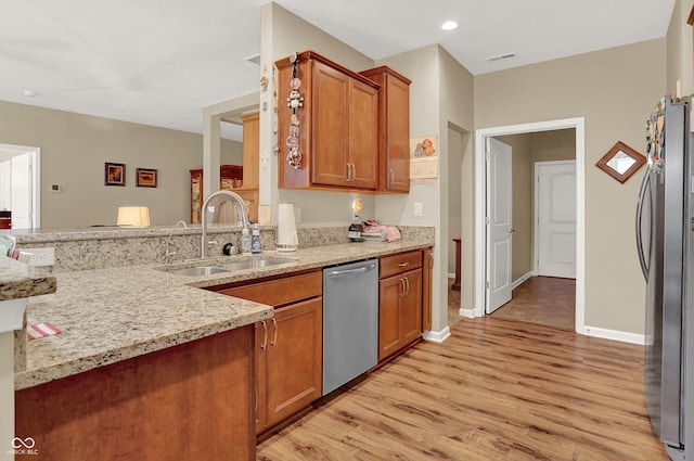 kitchen with light wood-style flooring, a sink, stainless steel appliances, brown cabinetry, and visible vents