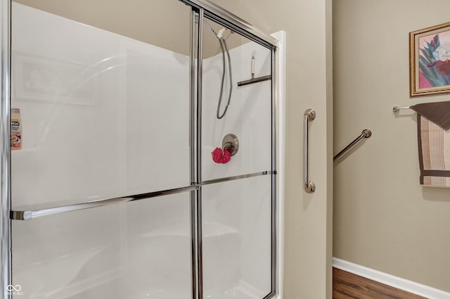 bathroom featuring baseboards, a shower stall, and wood finished floors