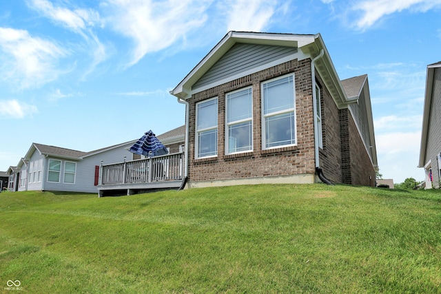 exterior space featuring a deck, brick siding, and a lawn