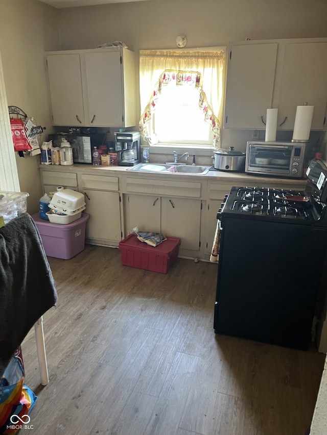 1420 Indiana Ave, New Castle, IN 47362 - kitchen with gas stove, light wood-type flooring, white cabinets, and a sink