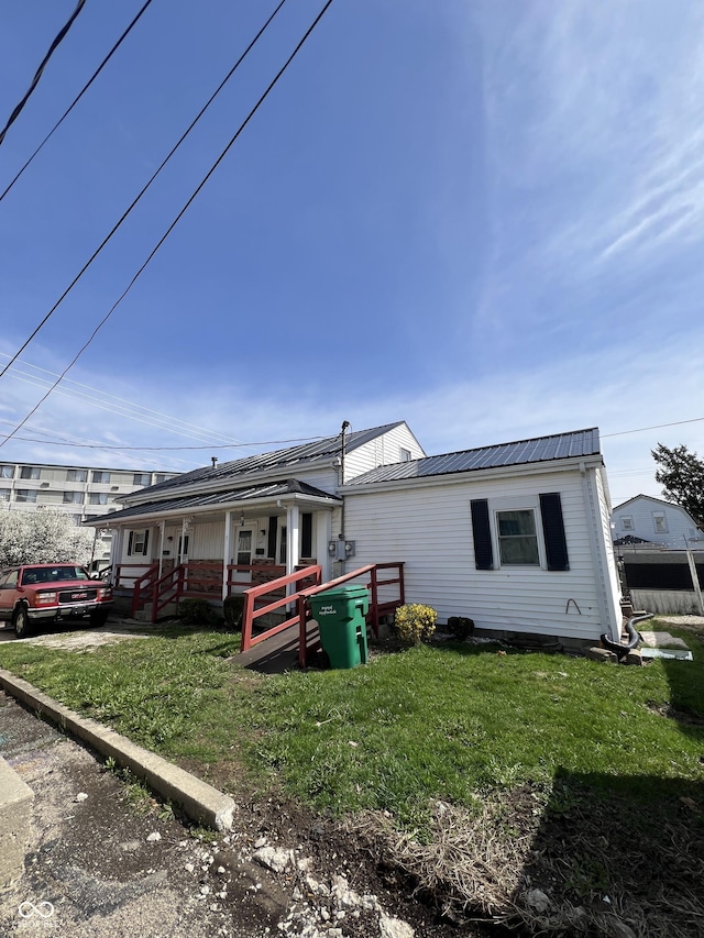 rear view of property featuring a porch, metal roof, and a yard