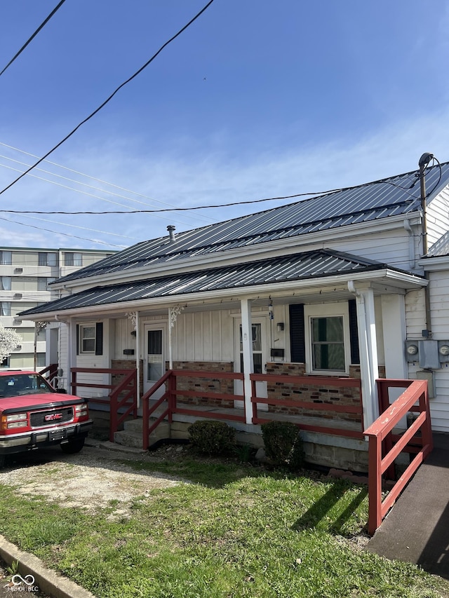 bungalow-style house with a porch, metal roof, and a front lawn