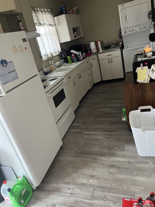 kitchen with white appliances, stacked washer / dryer, wood finished floors, white cabinets, and a sink